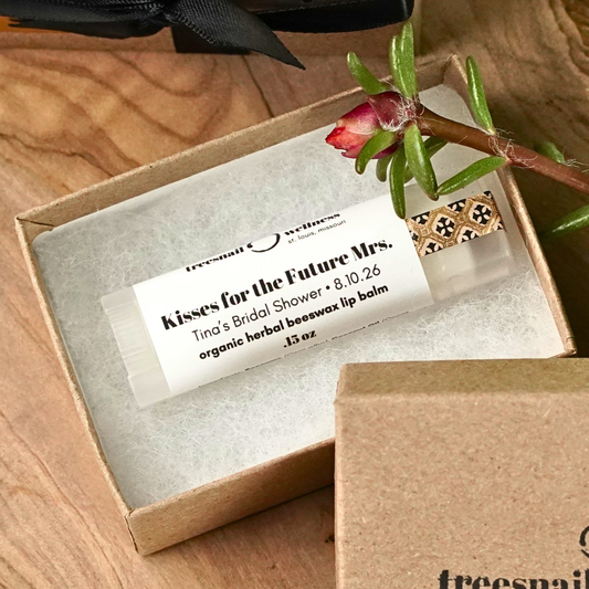 Lip balm in a box with a label and a flower on a wooden surface