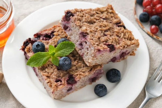 blueberry oatmeal bars with whole blueberries and fresh mint on a white plate