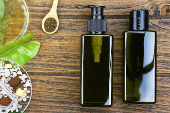 green skincare product bottles next to a spoon and plants