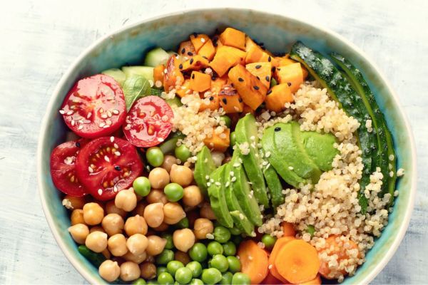 Tomatoes, avocado, chick peas, quinoa, peas, carrots in a bowl