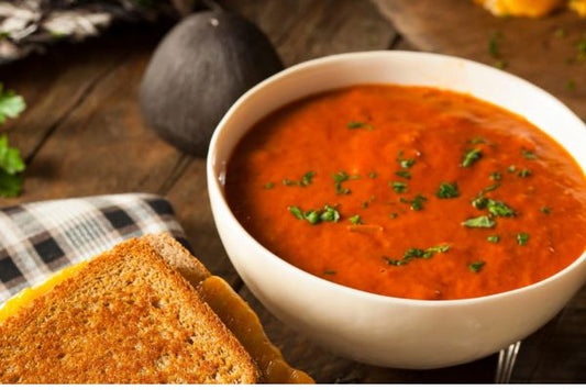 tomato soup with basil next to a grilled cheese sandwich