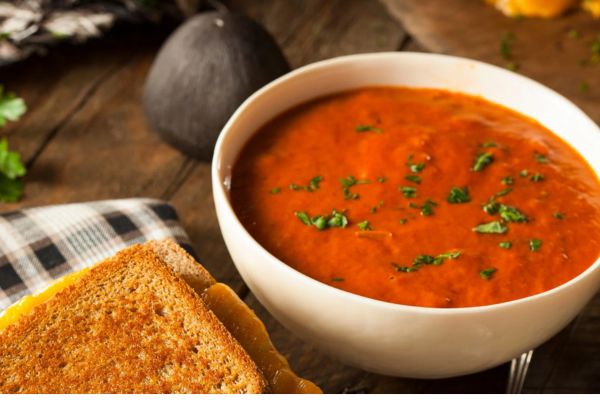 tomato soup with basil next to a grilled cheese sandwich