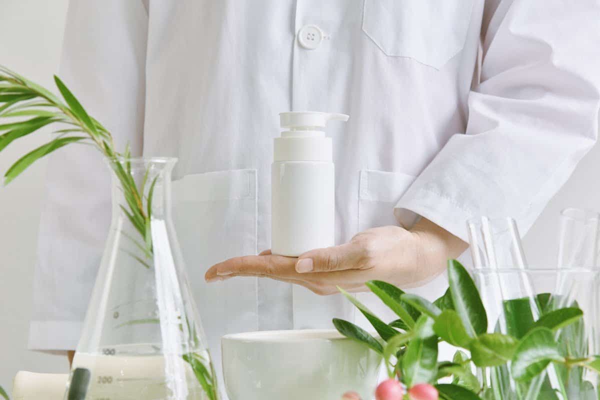 woman in a white lab coat holding a white skincare bottle