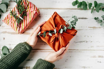 woman holding a gift tied with fabric and embellished with eucalyptus