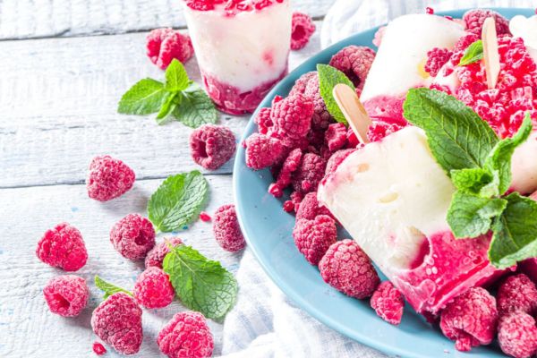 Greek yogurt popsicles surrounded by raspberries and mint leaves