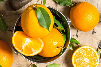 whole oranges and cut oranges in a bowl