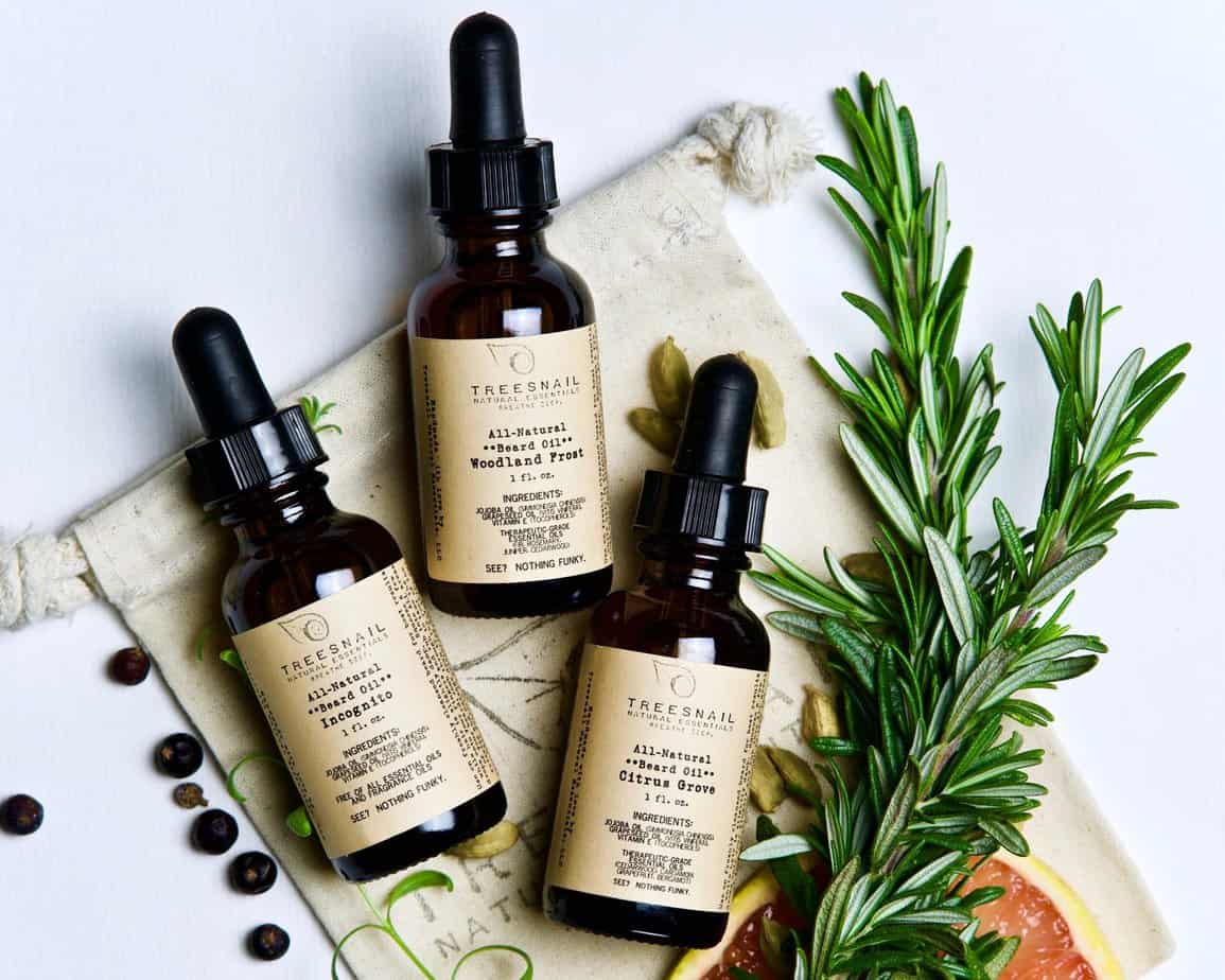 3 natural beard oil bottles laying with rosemary