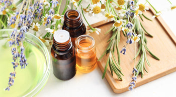 Essential oils next to lavender, chamomile, and rosemary.