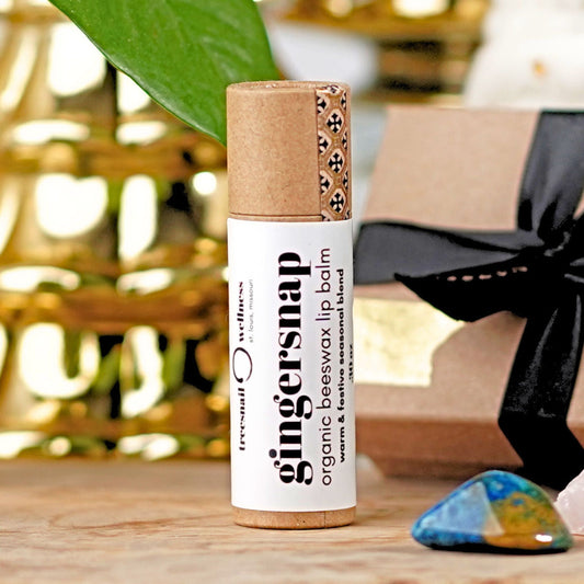 Gingersnap organic beeswax lip balm on a wooden surface with a blurred background by Treesnail Wellness