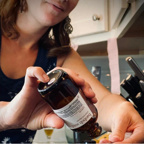 Christine Glaser holding a small brown bottle making skincare products in a kitchen setting