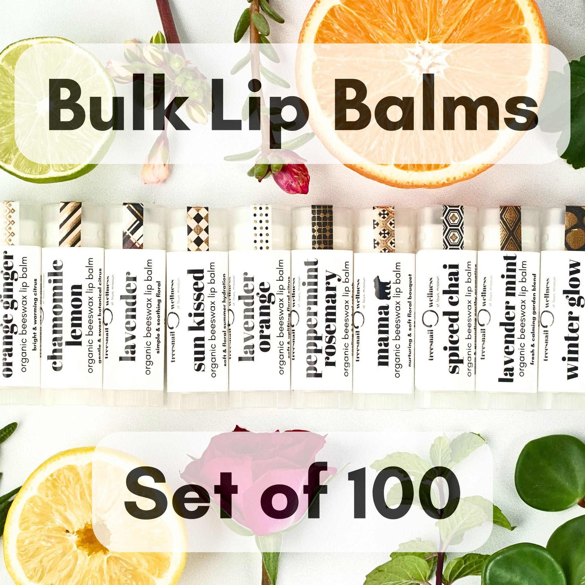 Set of 100 bulk organic lip balms with various scents surrounded by fruits and leaves.