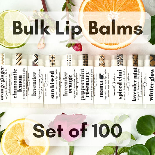 Set of 100 bulk organic lip balms with various scents surrounded by fruits and leaves.
