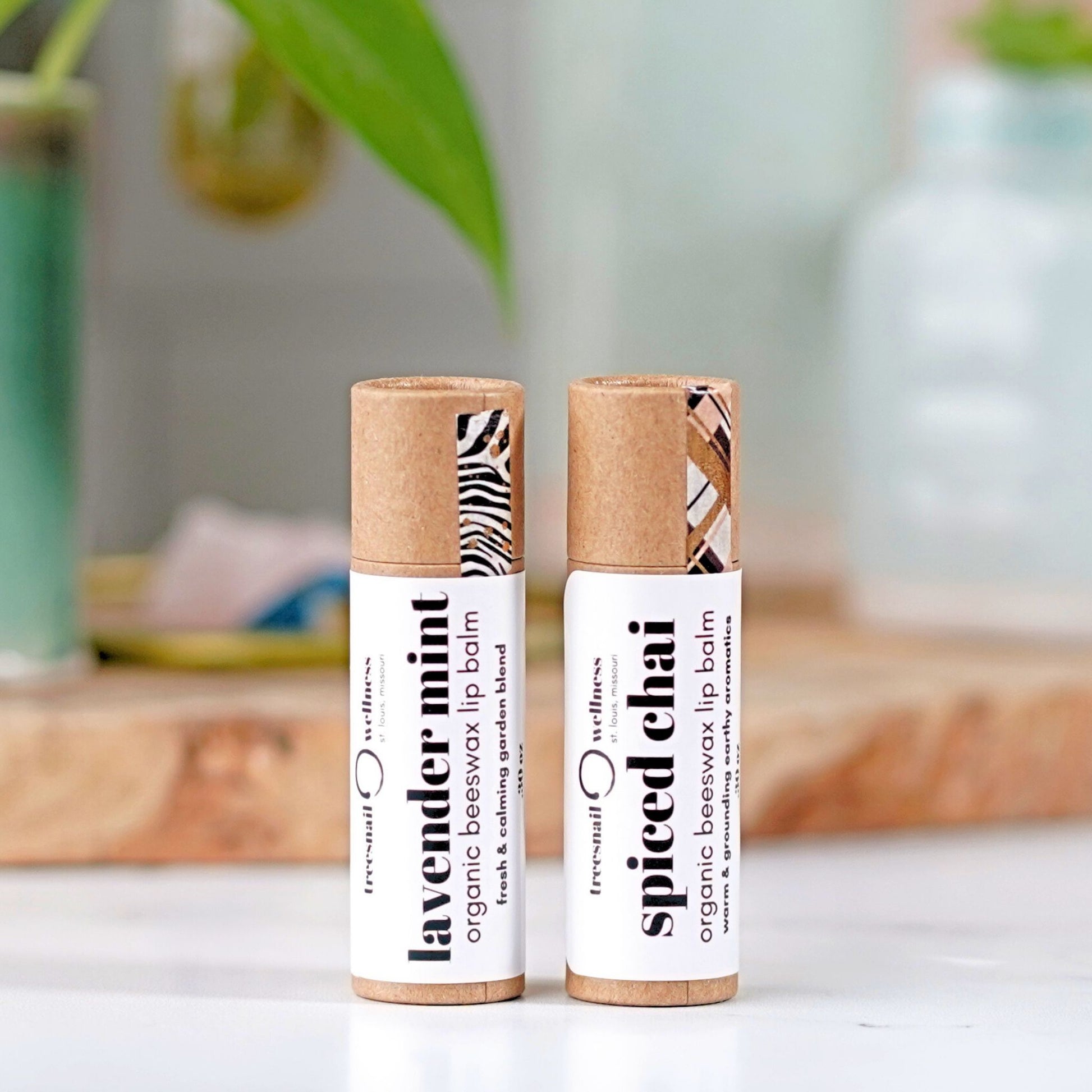 Two organic beeswax lip balm tubes on a white surface with a blurred background