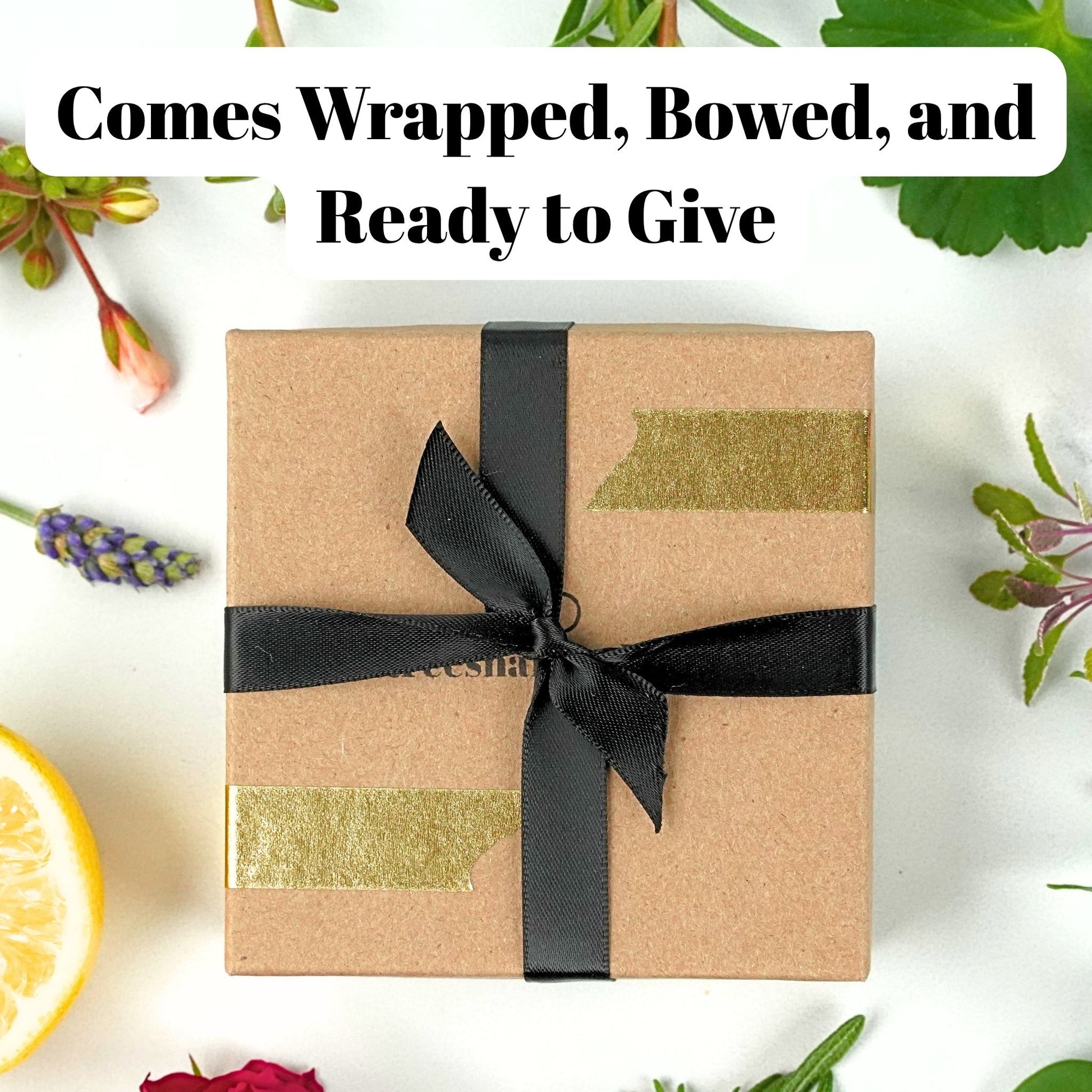 Gift box wrapped in brown paper with a black ribbon on a white background with flowers.