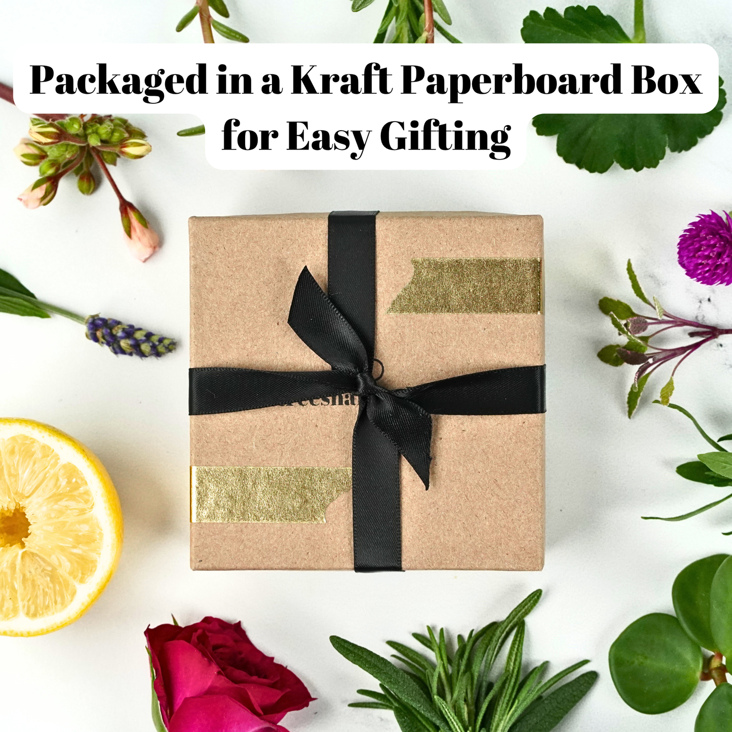 Gift box wrapped in brown paper with a black ribbon, surrounded by flowers and herbs on a white background.